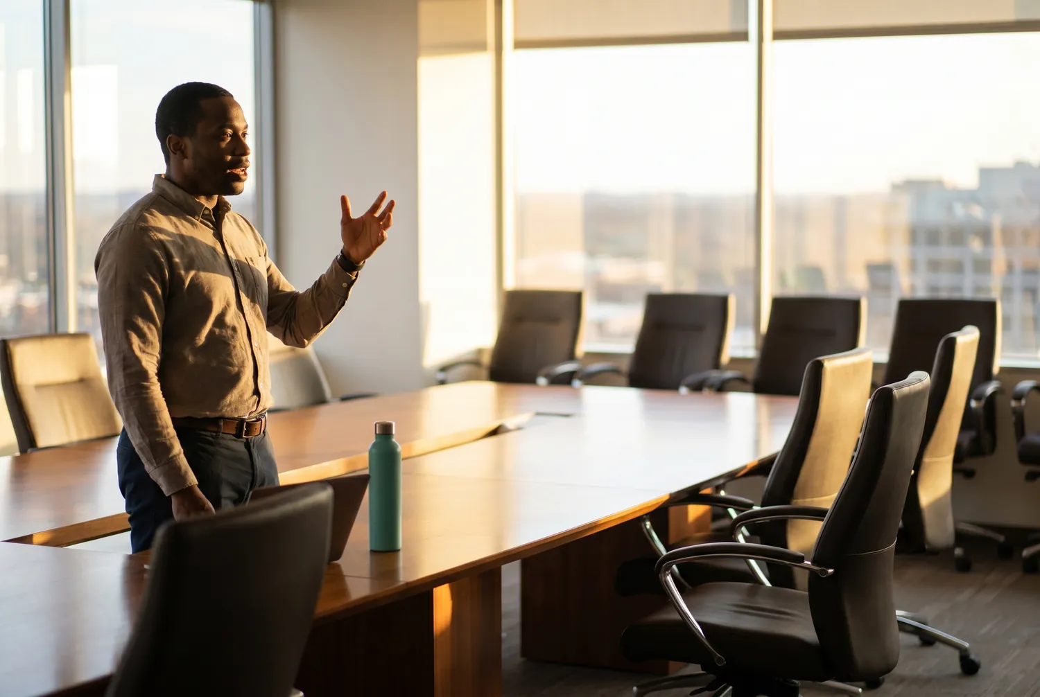 Man rehearsing a presentation alone in an empty conference room with a single teal water bottle on the table Man rehearsing a presentation alone in an empty conference room with a single teal water bottle on the table