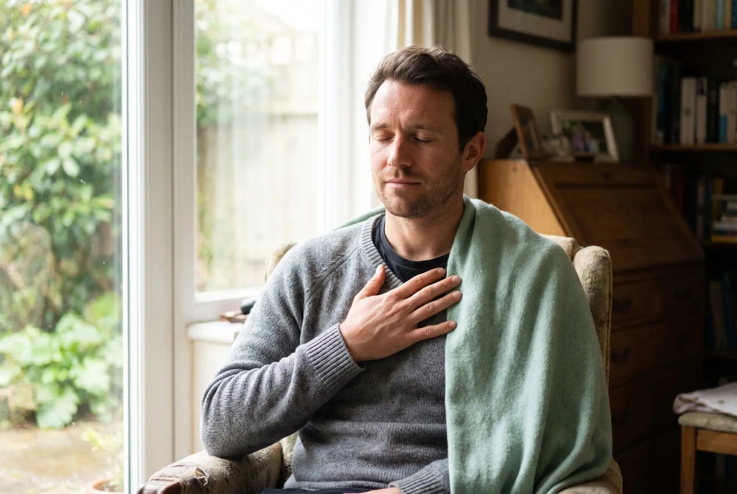 A man breathing calmly by a window after a wave of panic passes