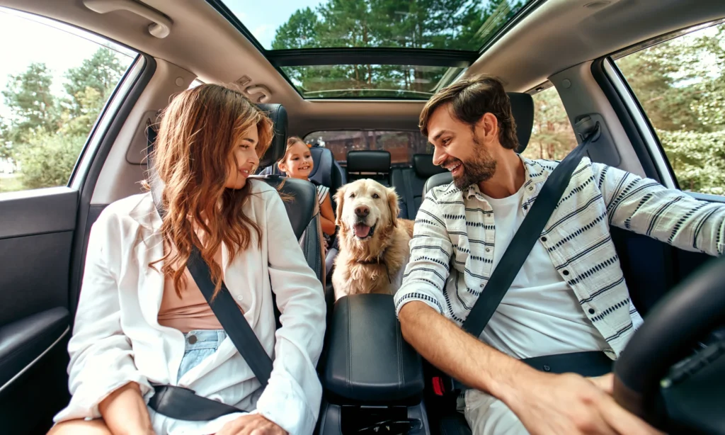 Happy family in parked car looking at dog