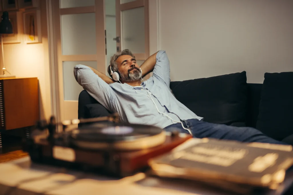 man relaxing on couch with feet out and listening to music