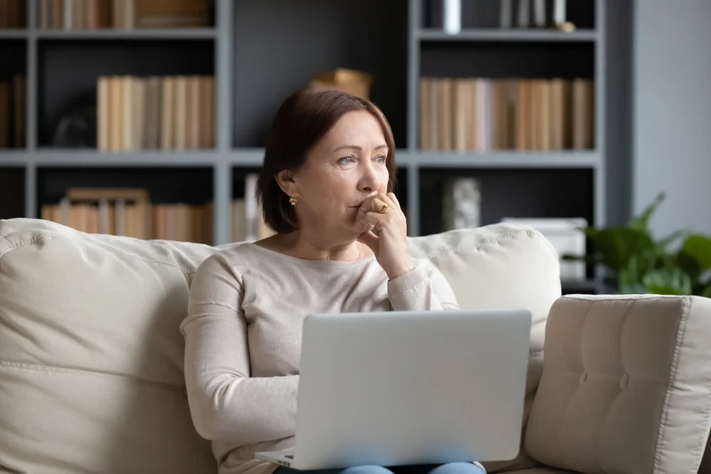 woman with laptop on her lap looking off into the distance