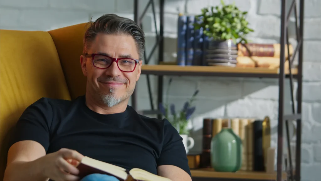 man smiling on couch while reading