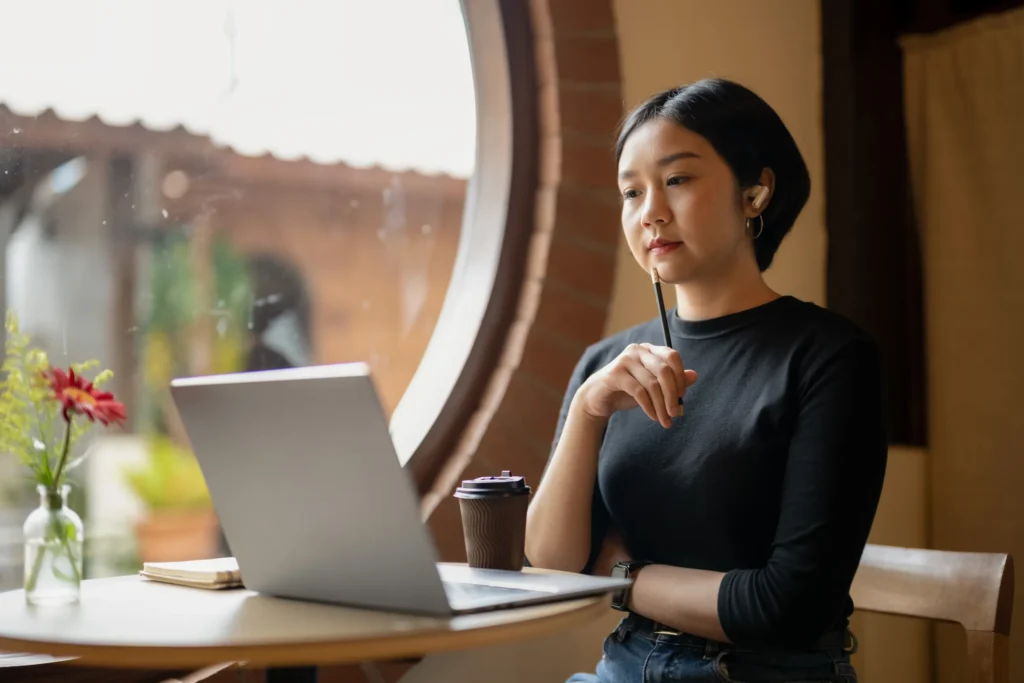 woman with computer in front of her and pencil in hand