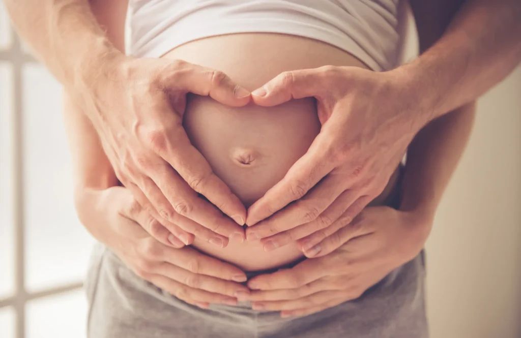 close up of hands on pregnant woman's belly