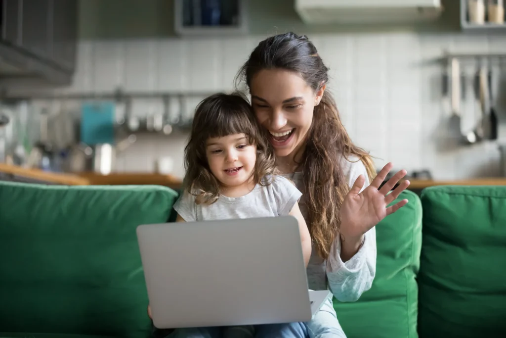 mother has her young daughter on her lap looking at computer screen