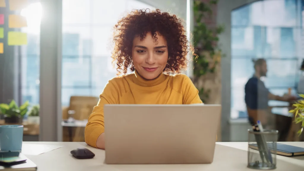 woman smiling and looking at laptop screen