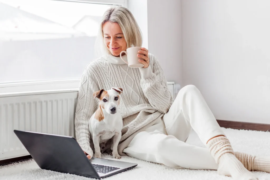 woman sitting with her dog smiling and working