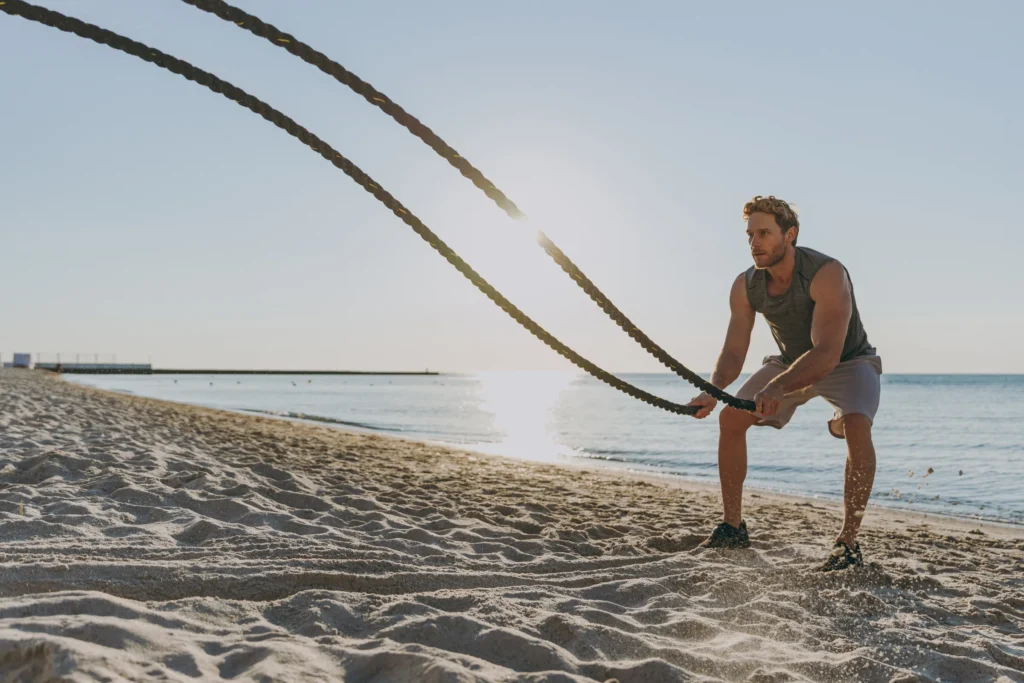 man working out on the beach with battle ropes