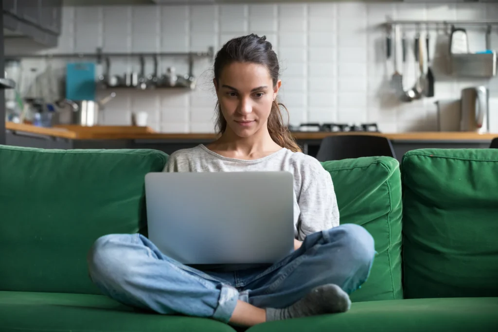 woman sitting crosslegged on couch with laptop