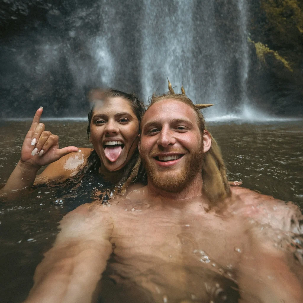 couple in lake taking a selfie near a waterfall