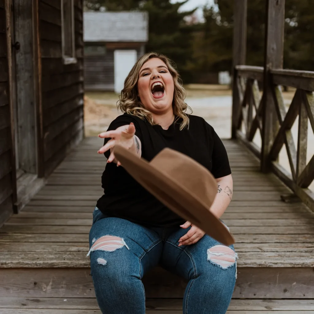 Woman sitting on bridge throwing her hat