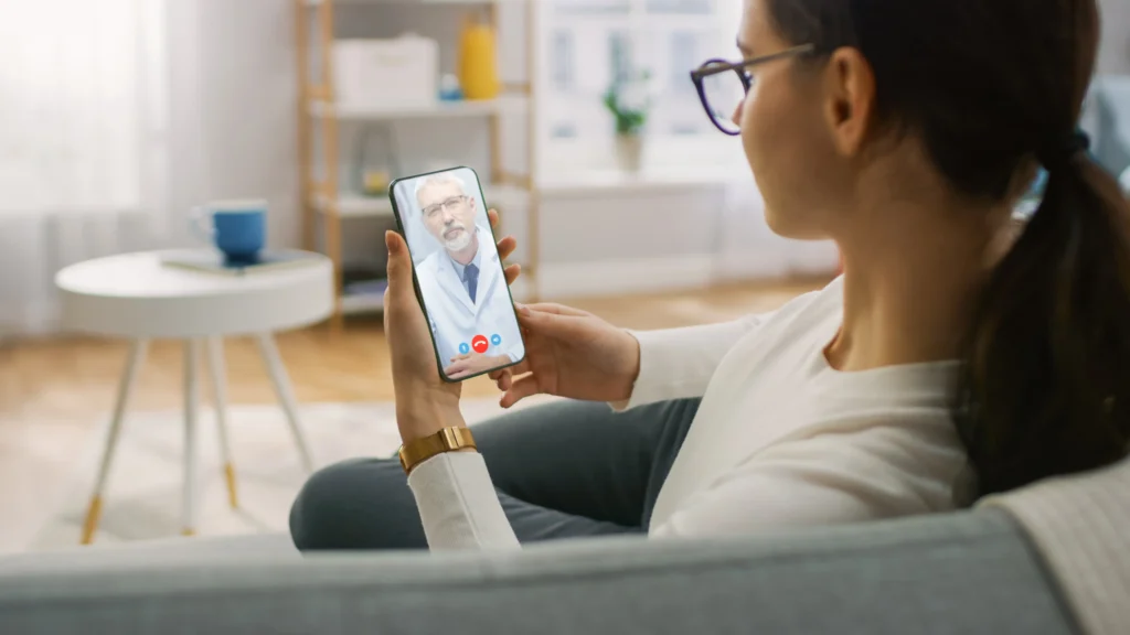 Woman on couch video chatting with a doctor