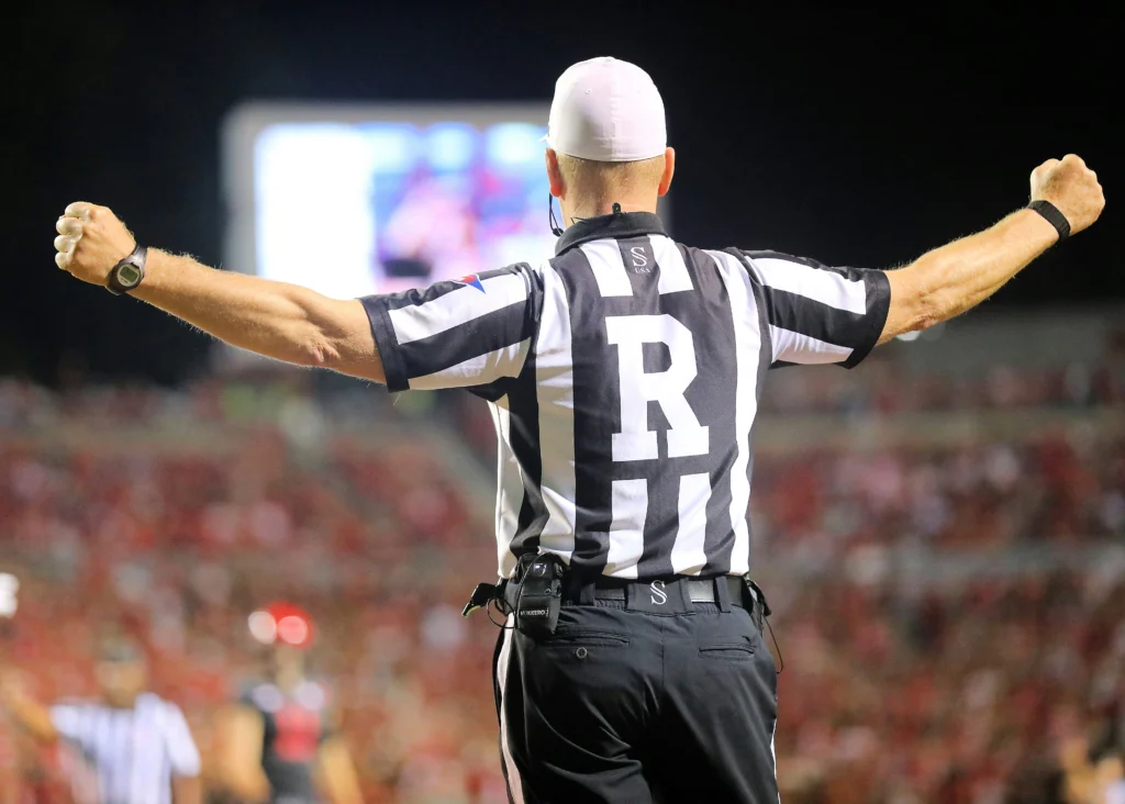 NFL referee with arms raised high in celebration under stadium lights, illustrating high-pressure moments and mental intensity in football like the Super Bowl