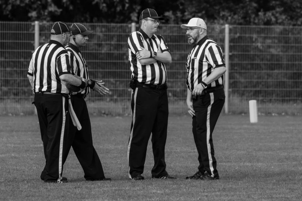 Sports referees discussing a call on the field, symbolizing pressure, scrutiny, and the mental health impact of high-stakes sporting moments